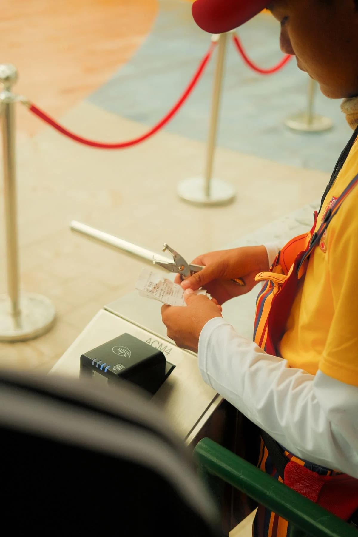 An attendant checking a paper ticket at an entrance beside a ticket reader